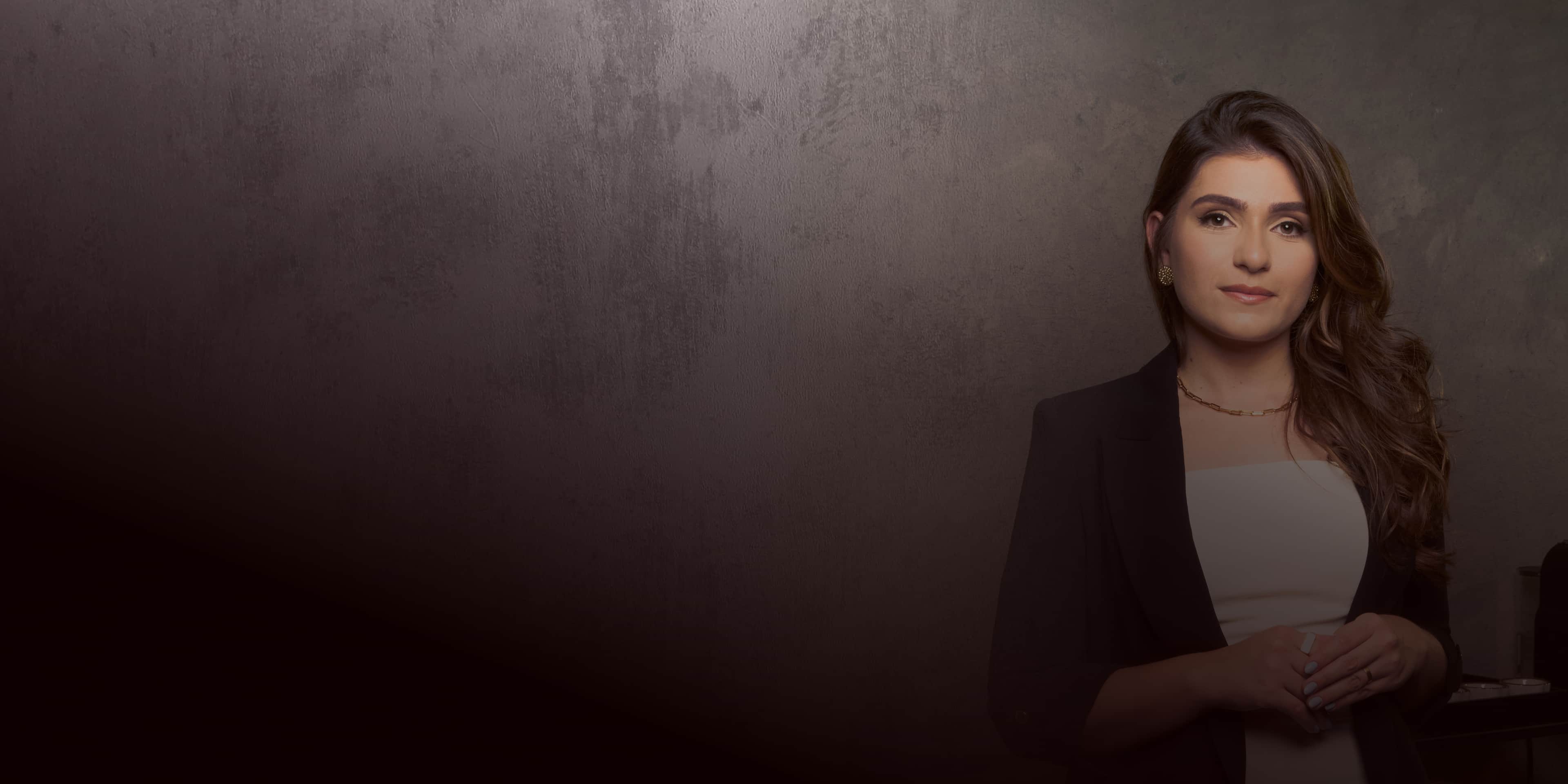 Banner do escritório de advocacia Isabel Pimenta. Uma imagem de uma mulher com cabelo castanho castanho e liso, usando uma roupa preta e branca, com um fundo morrom borrado.
